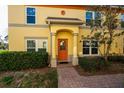 Inviting front entrance with an orange door, trimmed columns, and manicured landscaping, exudes classic comfort and style at 122 Coquina Bay Dr, St Petersburg, FL 33705