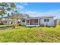 Exterior view of the house showing its light blue color, carport, and enclosed front porch at 130 81St Ne Ave, St Petersburg, FL 33701
