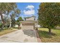 This lovely two-story home boasts a neutral tan exterior with an attached two-car garage and brick-lined driveway at 15701 Greyrock Dr, Spring Hill, FL 34610