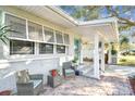 Inviting front porch with cozy seating area, brick flooring, and a turquoise front door at 349 Shirley Ave, Belleair, FL 33756