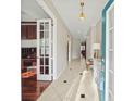 Bright foyer features tiled floors, a decorative light fixture, and views into adjacent rooms through paneled glass doors at 5229 Brighton Shore Dr, Apollo Beach, FL 33572