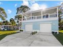 Two-story raised beach house with two-car garage, a spacious driveway and an open balcony at 6841 Oelsner St, New Port Richey, FL 34652