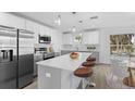 Modern kitchen featuring stainless steel appliances, a central island with seating and white cabinetry at 6841 Oelsner St, New Port Richey, FL 34652