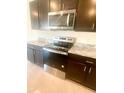 Close-up view of stainless steel oven and microwave, complemented by granite countertops at 2714 Lotus Flower Trl, Wesley Chapel, FL 33543