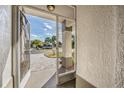 View from screened doorway onto a paved driveway and palm trees under a blue sky at 29307 Schinnecock Hills Ln, San Antonio, FL 33576