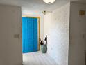 Bright foyer featuring a blue front door, white brick accent wall, light hardwood flooring, and an umbrella stand at 4233 Abaco Ct, New Port Richey, FL 34653