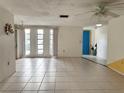 Open-plan living room and foyer featuring tile floors, bright windows, and a colorful blue front door at 4233 Abaco Ct, New Port Richey, FL 34653