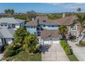 Birds-eye view of a charming blue home featuring a large driveway, a well-manicured lawn, and lush landscaping at 7284 Pebble Beach Ln, Seminole, FL 33777