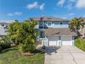 Aerial view of a blue two-story home with a two-car garage, well-kept lawn, and tropical landscaping at 7284 Pebble Beach Ln, Seminole, FL 33777