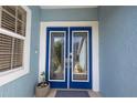 Close-up of the home's elegant double front doors, with decorative glass and a fresh blue finish at 7284 Pebble Beach Ln, Seminole, FL 33777