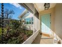 Covered front porch with a turquoise front door, rain chains, and well kept landscaping at 9940 69Th N St, Pinellas Park, FL 33782