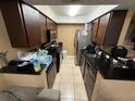 Galley style kitchen featuring dark cabinetry, stainless steel refrigerator, and tile flooring at 13915 Village View Dr, Tampa, FL 33624