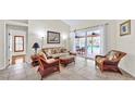 Bright living room with tile floors, sliding glass doors leading to a screened pool, and tropical furnishings at 140 Sage Cir, Crystal Beach, FL 34681