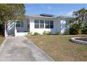 Inviting white home with solar panels, complemented by a concrete driveway and green landscaping at 4415 4Th S Ave, St Petersburg, FL 33711