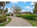 Inviting single-story home featuring a tile roof, brick-paved driveway, lush landscaping, and a two-car garage at 710 Treasure Boat Way, Sarasota, FL 34242