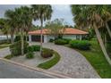 Charming single-story home with a vibrant tile roof, lush landscaping, and a gracefully curving brick driveway at 710 Treasure Boat Way, Sarasota, FL 34242
