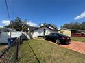Features of a well-kept, single-story home with a lush green lawn and black car at 8706 N Boulevard, Tampa, FL 33604