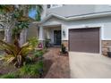 Inviting home entrance with covered porch, brick walkway, stone accents, and lush landscaping at 1002 Vineyard Ln, Oldsmar, FL 34677