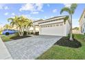 Wide brick driveway leading to a two-car garage, surrounded by lush landscaping at 310 Blackrock Ln, Apollo Beach, FL 33572