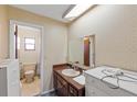 Neutral bathroom with tiled walls, vanity, and a doorway leading to the toilet and shower at 38928 Tall Dr, Zephyrhills, FL 33540