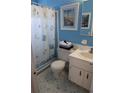 Bright blue bathroom with tiled floors, framed lighthouse art and a shower with a themed curtain at 6188 Pinehurst Dr, Spring Hill, FL 34606