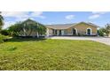 Beautiful home with a lush green lawn, mature palm trees, and an inviting circular driveway at 12769 Foresman Blvd, Port Charlotte, FL 33981