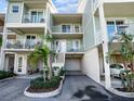 Exterior of a three-story townhouse featuring pale green siding, white railings, a garage, and tropical landscaping at 3266 Mangrove Point Dr, Ruskin, FL 33570