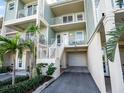 Close-up exterior of a three-story townhouse featuring pale green siding, white railings, and garage at 3266 Mangrove Point Dr, Ruskin, FL 33570