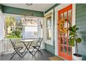 Charming front porch with an inviting seating arrangement, decorative hanging art, and vibrant door at 202 13Th N Ave, St Petersburg, FL 33701