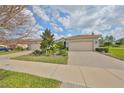 Charming home featuring a well-manicured lawn, professional landscaping, and a brick paver driveway to the two-car garage at 4903 Avila Lakes Dr, Wimauma, FL 33598