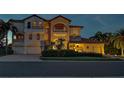 Luxury home exterior, illuminated at dusk, features a three-car garage at 109 Wateredge Ct, Safety Harbor, FL 34695