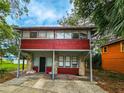 Two-story home with a red exterior, and a small front yard with a covered carport at 1414 7Th S St, St Petersburg, FL 33701