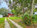 View of home's ample lot with mature trees and an orange flowering bush at 1414 7Th S St, St Petersburg, FL 33701