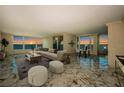 Light-filled living room with marble floors, neutral furniture, and floor-to-ceiling windows with ocean views at 634 Edgewater Dr # 644, Dunedin, FL 34698