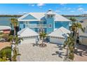 Beautiful blue coastal home with a metal roof, three-car garage and lush landscaping at 295 Bayside Dr, Clearwater Beach, FL 33767