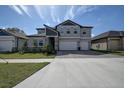 Two-story house with gray siding, stone accents, and a three-car garage at 12821 Bergstrom Bay Dr, Riverview, FL 33579