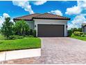 Two-car garage with paver driveway and lush green landscaping at 3134 Francoa Dr, Odessa, FL 33556