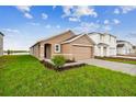 Tan one-story house with a two-car garage and landscaped lawn at 5552 Logan Cave Ave, Wimauma, FL 33598