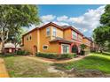 Tan townhome with red accents, lush landscaping, and a walkway at 2272 Chianti Pl # 4-0048, Palm Harbor, FL 34683