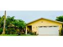 Bright yellow house with a white garage door and tropical landscaping at 1964 Arvis E Cir, Clearwater, FL 33764