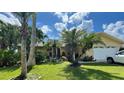 Inviting yellow house with palm trees, a well-manicured lawn, and a two-car garage at 1964 Arvis E Cir, Clearwater, FL 33764