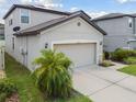 View of a home's two-car garage with gray exterior walls, and adjacent landscaping for curb appeal at 12235 Creek Preserve Dr, Riverview, FL 33579