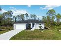 One-story house featuring a grey exterior, white garage, and green lawn at 9333 Hialeah Ter, Port Charlotte, FL 33981