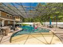 Large, screened pool area with a rock waterfall feature, swim-up bar, and spa at 601 Seven Oaks Ct, Brooksville, FL 34601