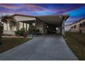 Mobile home exterior at dusk with carport and golf cart at 37527 El Sol Ave, Zephyrhills, FL 33541