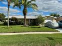 Tan, single-story home with a spacious front yard at 1354 Linstock Dr, Holiday, FL 34690