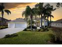 Stunning home exterior at sunset, featuring a three-car garage and manicured lawn at 13235 Legends Trl, Dade City, FL 33525