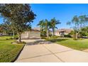 House exterior with a three car garage and driveway, surrounded by palm trees and green grass at 13235 Legends Trl, Dade City, FL 33525