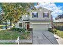 Two-story house with a green exterior, red door, and attached garage at 10724 Burning Bush Ter, Land O Lakes, FL 34638