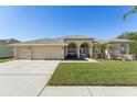 Single-story house featuring a three-car garage and well-manicured lawn at 7302 Melogold Cir, Land O Lakes, FL 34637